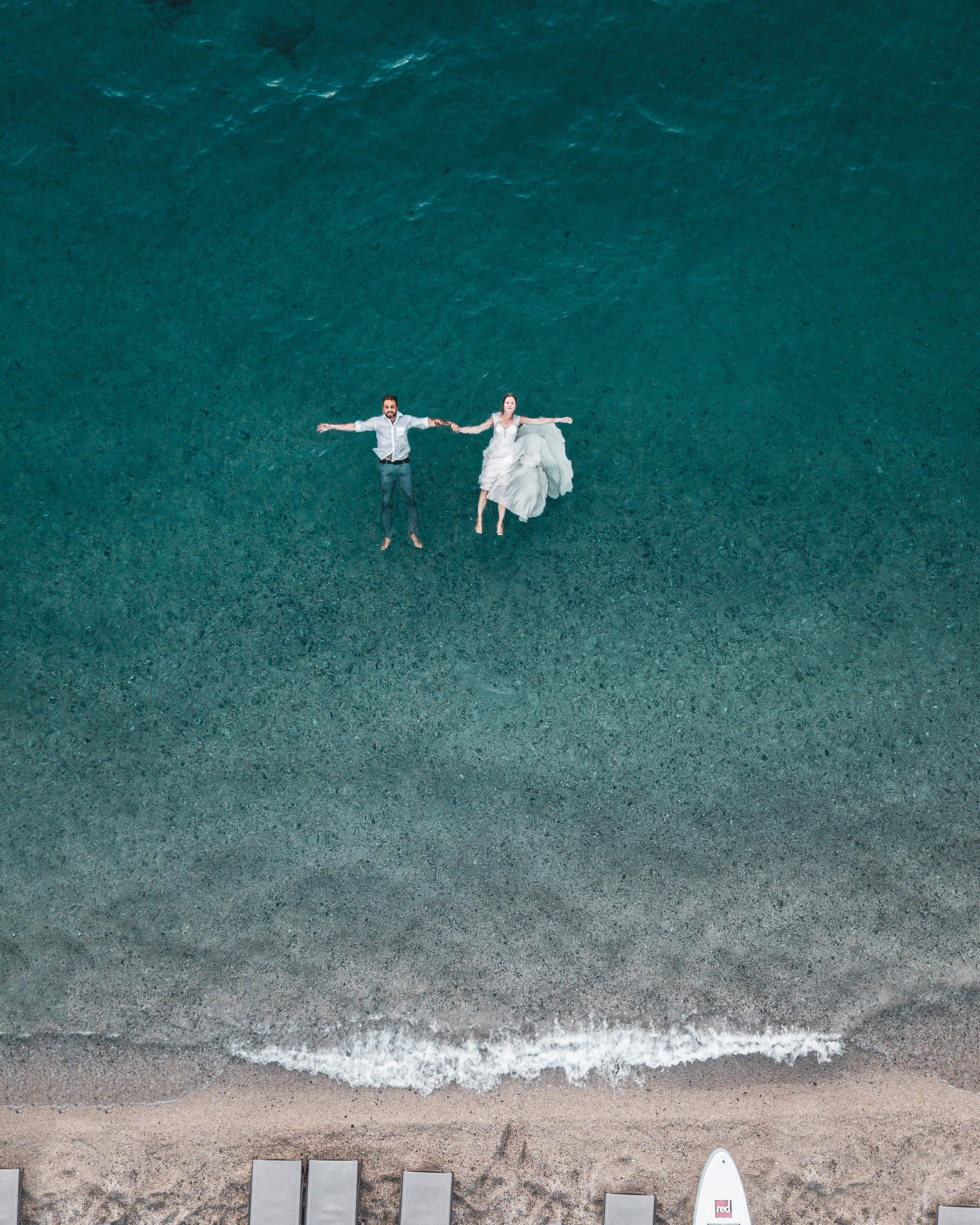 Drone flying over a couple floating on the ocean